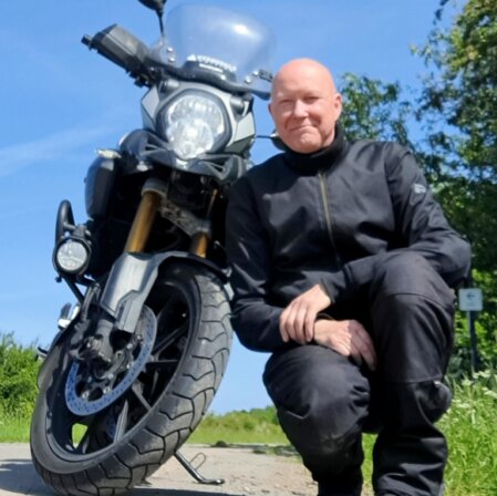 Porträt eines Motorradfahrers mit Tourenhelm vor dem Bike